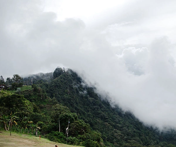 View of Las Nubes Park near Jericó, Colombia, with green mountains and cloudy sky.